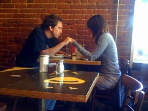 A couple hold hands and pray over their meal.